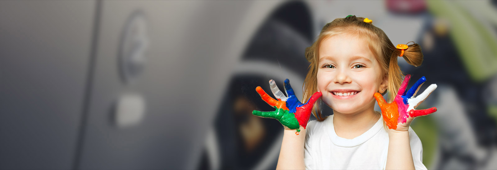 une petite fille sourinte les mains pleines de peintures